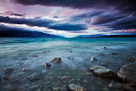 Evening colors appear in the sky over glacial blue Lake Pukaki. South Island, New Zealand.