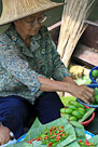 Woman sorting fruit and chillis at floating market, Bangkok, Thailand.